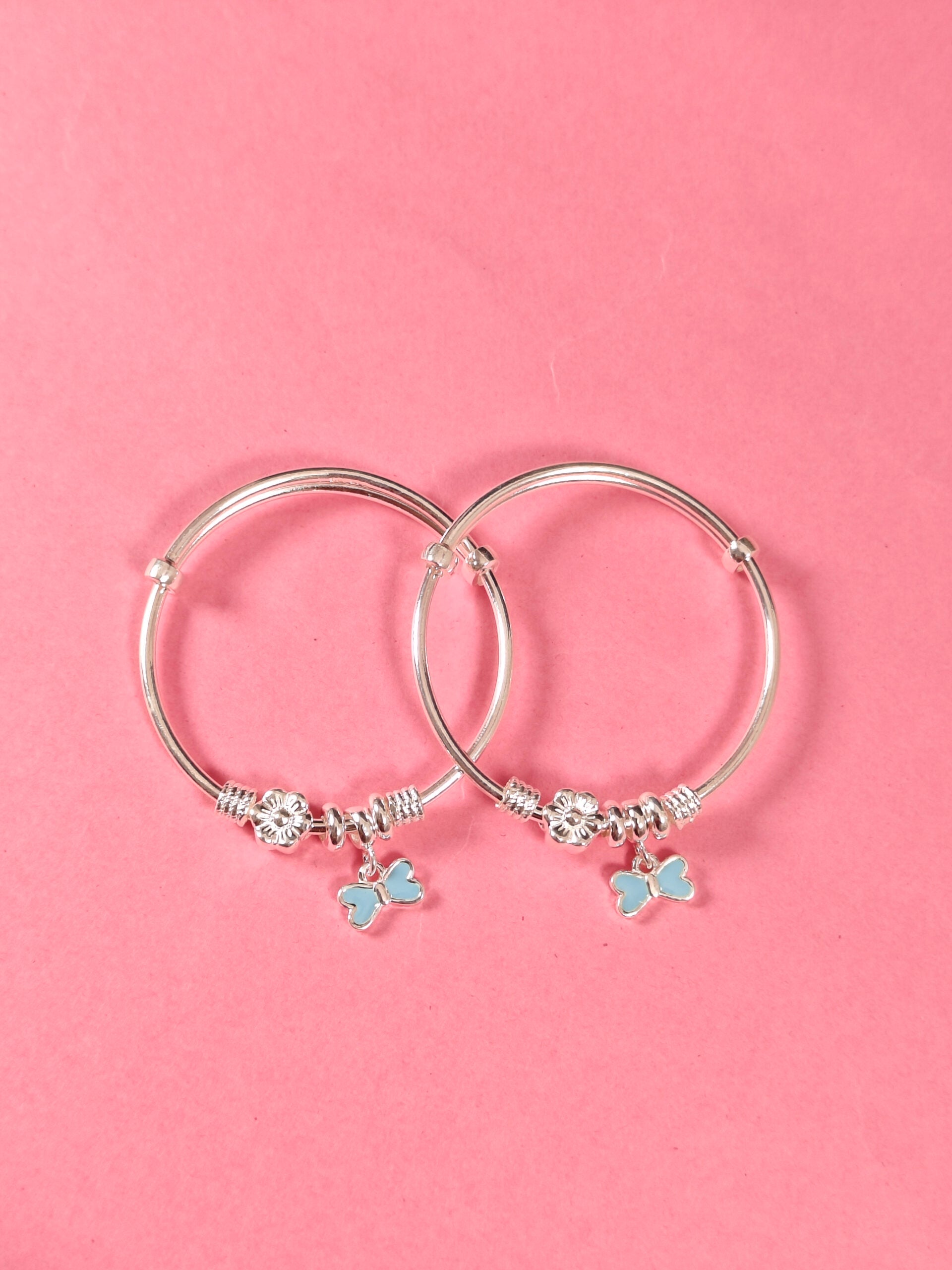 Silver hoop earrings with butterfly charms on a pink background